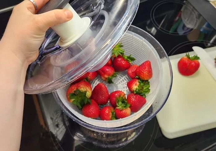 Preparing strawberries in a salad spinner, focusing on getting better at cooking.