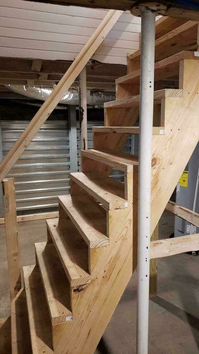 Escalera de madera mal construida en sótano, ejemplo de trabajo perezoso en la construcción.