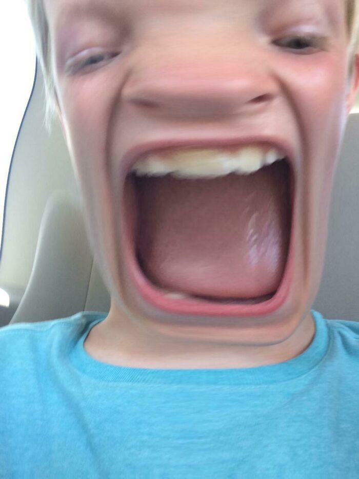 Distorted face of a child shouting with mouth wide open, representing hilarious kids in a funny moment.