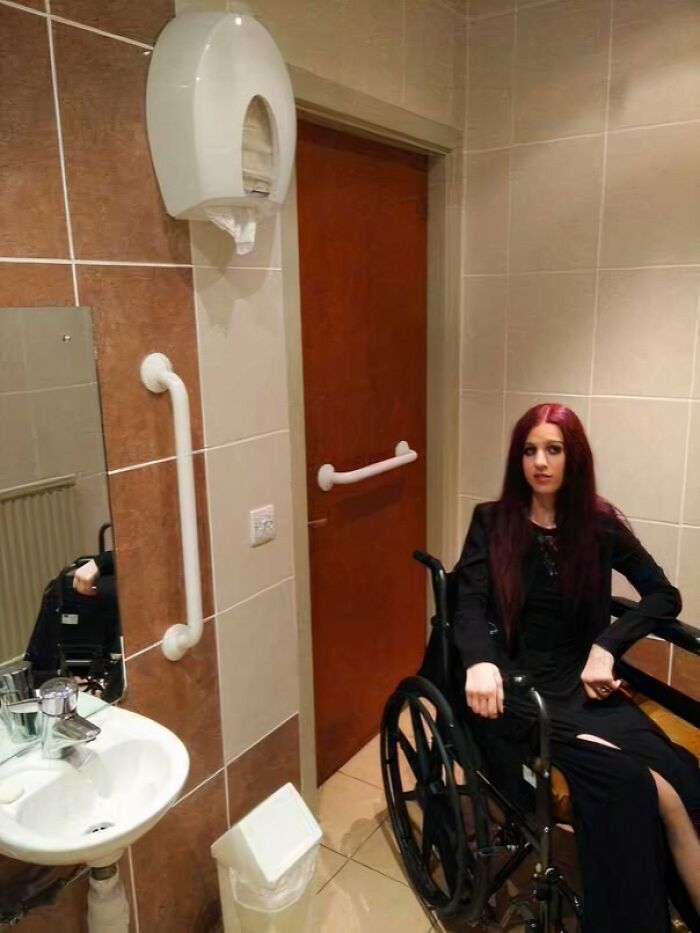 Persona en silla de ruedas en un baño con acceso bloqueado, destacando empleados perezosos en su diseño.