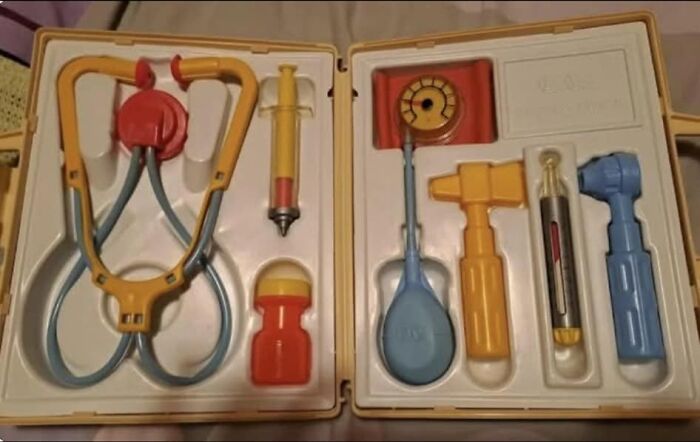 Vintage Gen X toy medical kit with stethoscope, syringe, and play tools arranged neatly in a yellow case.