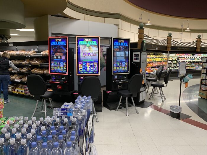 Slot machines unexpectedly placed in a grocery store aisle, showing unfortunate public interior designs.