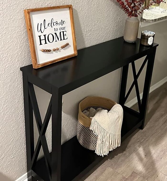 Smart furniture solution with a black console table, welcome sign, and basket in a small living space.