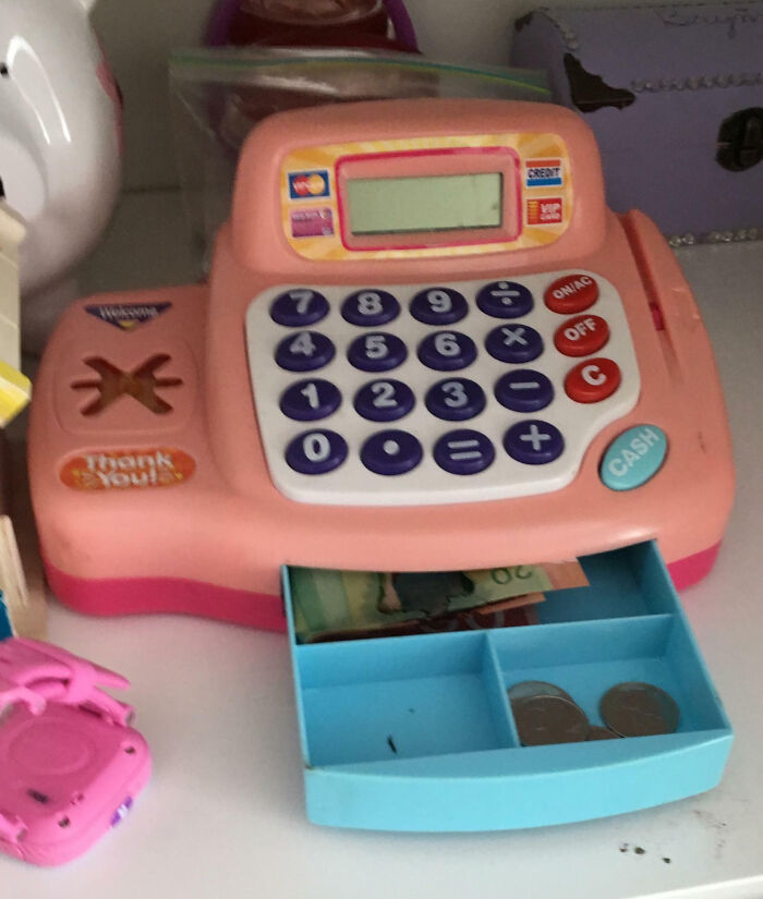 A toy cash register with play money, representing hilarious-kids playing store games.