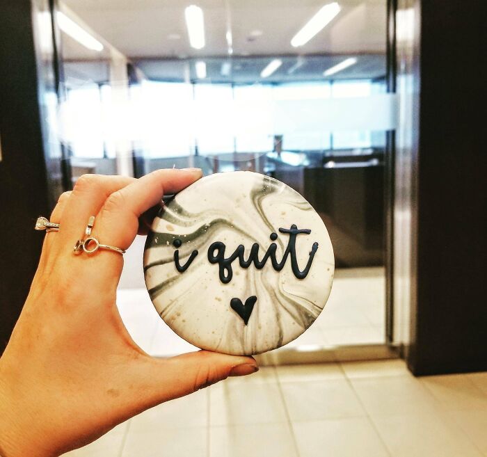 Person holding a round paperweight with "I quit" text, symbolizing people quitting jobs.