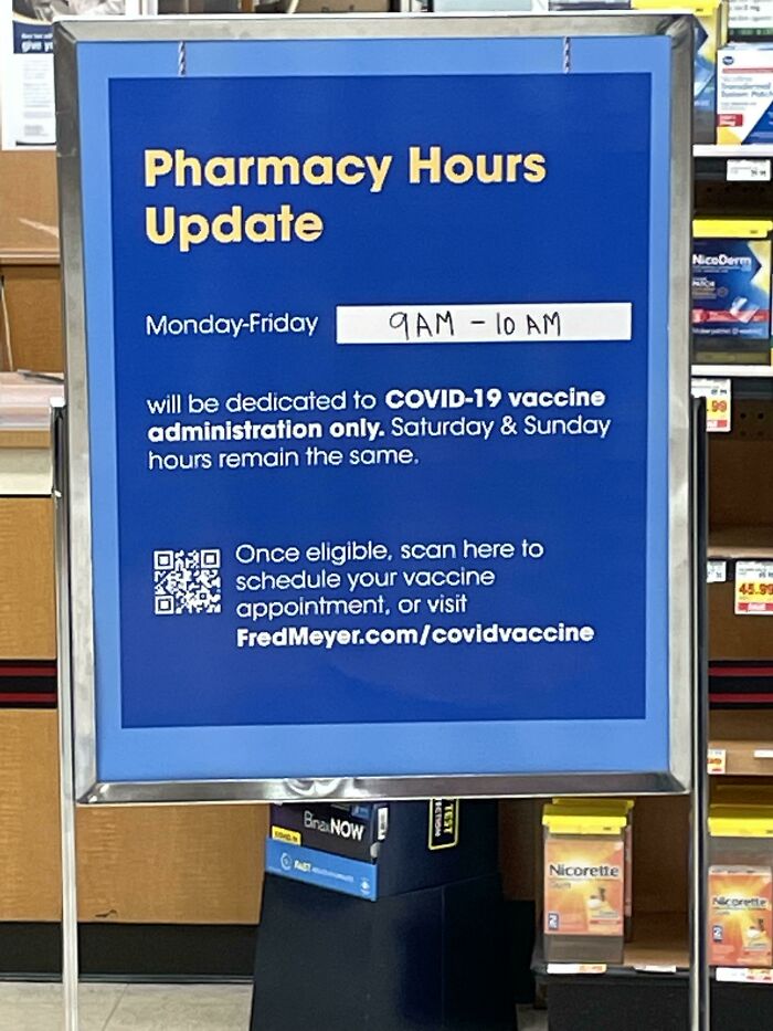 Sign displaying local pharmacies' adjusted hours for COVID-19 vaccine administration, Monday-Friday, 9 AM-10 AM.