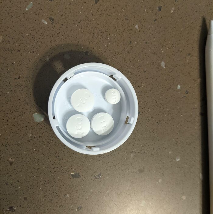 Pills arranged inside a prescription bottle cap on a countertop, highlighting local pharmacies.