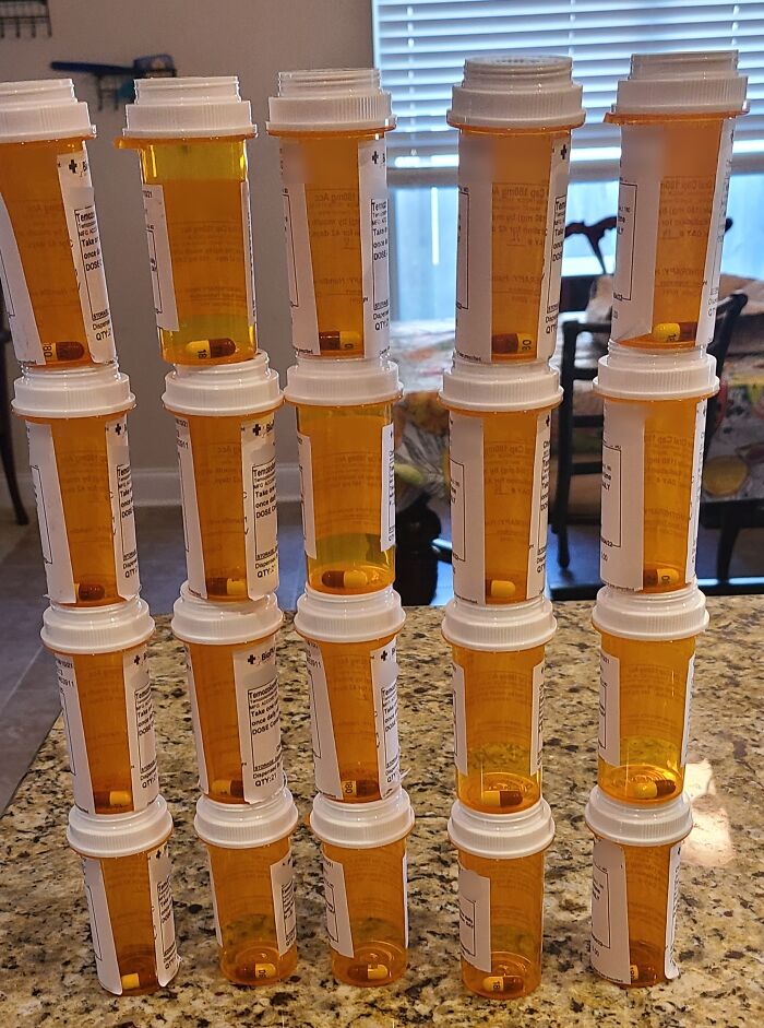 Tall stack of pill bottles on a kitchen counter highlighting issues with local pharmacies.