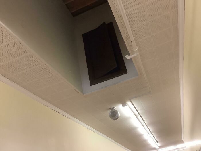 Ceiling with an unexpected open hatch, illustrating unfortunate interior design choices in a public space.