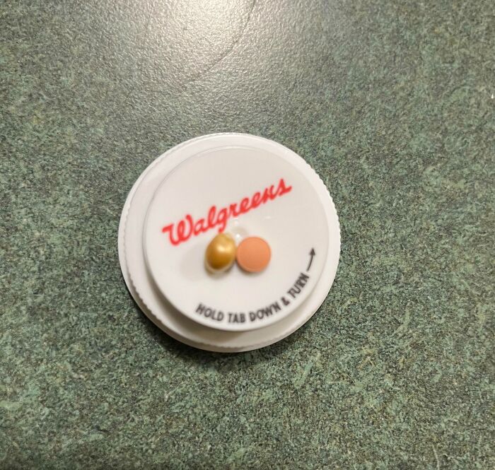 Pill bottle lid from a local pharmacy with two pills on top, reflecting infuriating service issues.