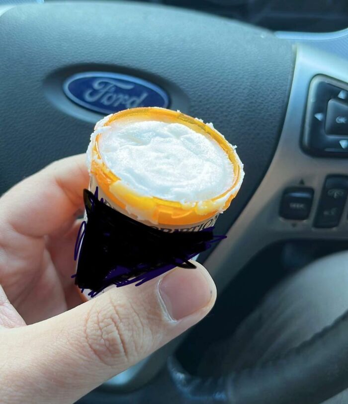 Hand holding a prescription bottle with an uneven, messy cap inside a car, highlighting frustrating local pharmacies.