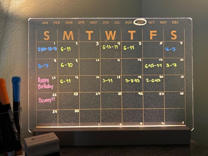 LED calendar planner for remote workers with schedule notes in bright colors next to pens.