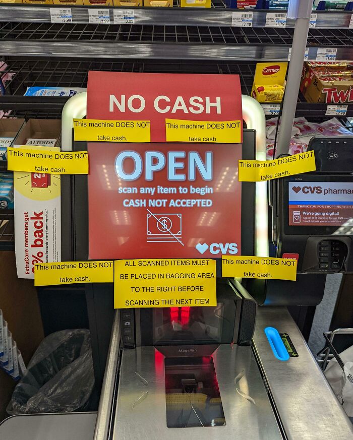 Pharmacy self-checkout machine displaying multiple signs stating cash not accepted, causing frustration.