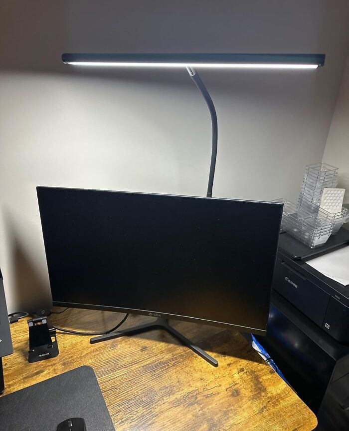 Curved monitor and desk lamp setup, an elegant upgrade for remote workers.