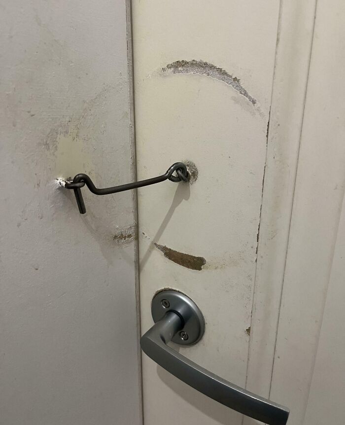 Worn-down door with metal latch and handle, showing passage of time through scratches and marks.