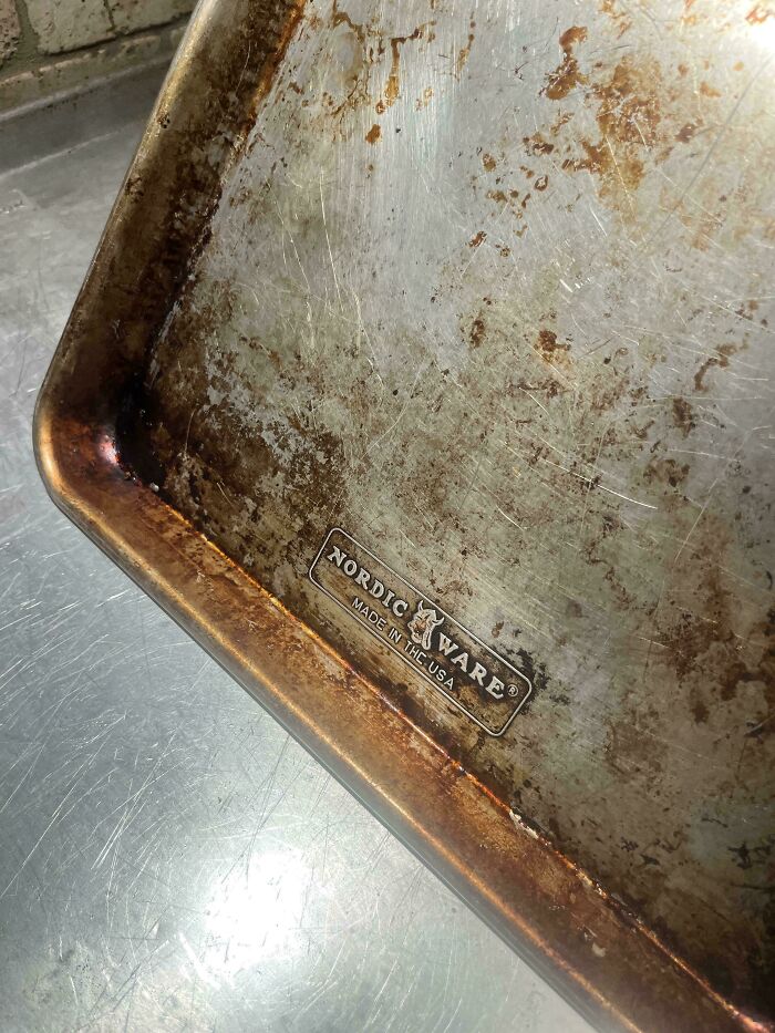 Worn-down baking sheet showing signs of aging and time-related wear, with Nordic Ware branding.