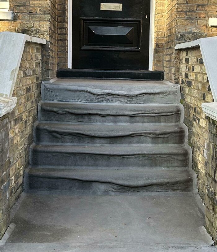 Worn-down stone steps in front of a brick house entrance, illustrating how time affects surfaces.