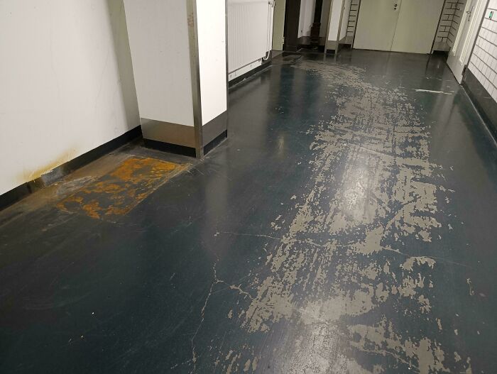 Worn-down hallway floor showing the effects of time through faded and scratched surface.