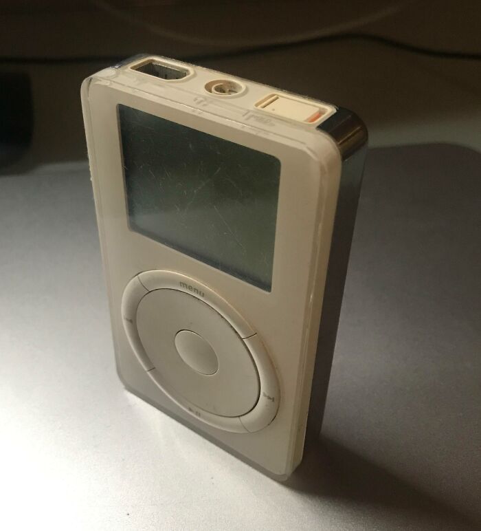 Worn-down iPod illustrating how time works, with scratches and faded buttons on a gray surface.