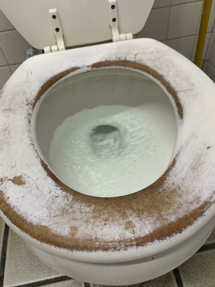 Worn-down toilet seat showing effects of time with visible discoloration and wear marks, illustrating time's impact.