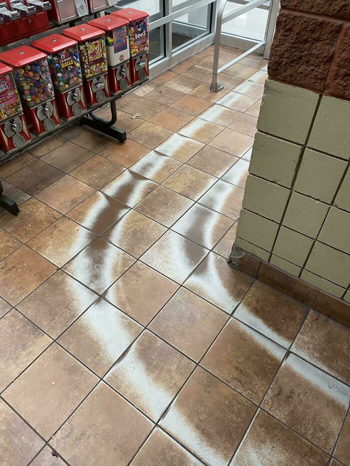 Worn-down floor tiles with visible paths of foot traffic in front of a row of vending machines.