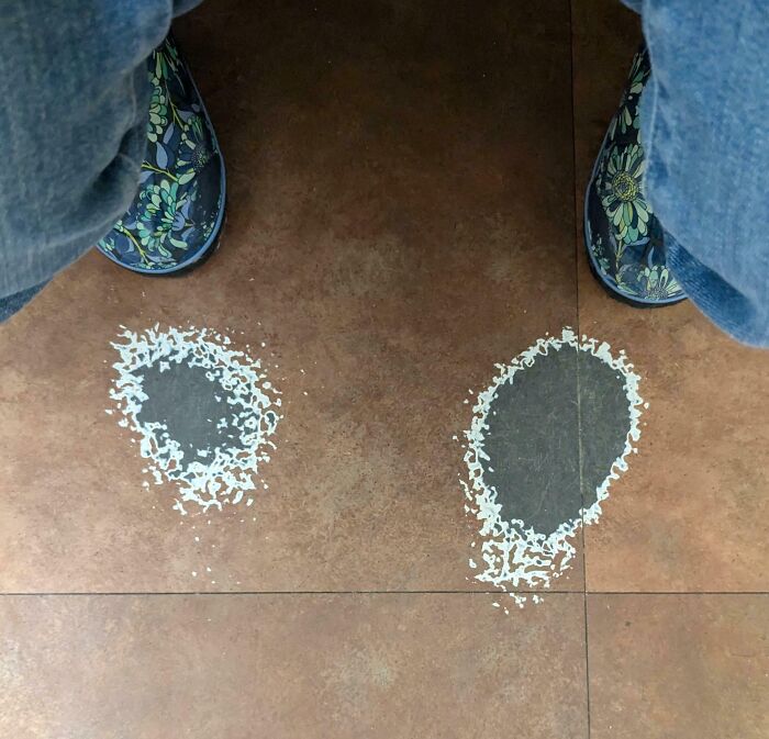 Worn-down floor tiles with faded spots under colorful, floral-patterned shoes, illustrating time's effect.