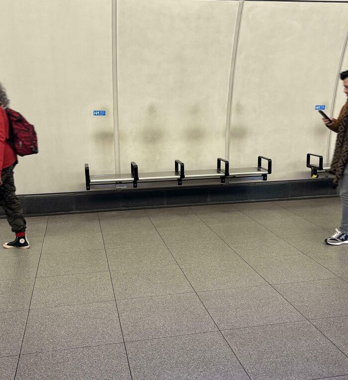 Worn-down wall with marks above metal seating in a subway, illustrating the passage of time.