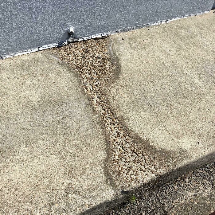 Worn-down concrete path showing erosion and exposed gravel, illustrating how time works on surfaces.