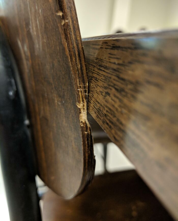 Close-up of a worn-down wooden chair showing visible signs of age and erosion.