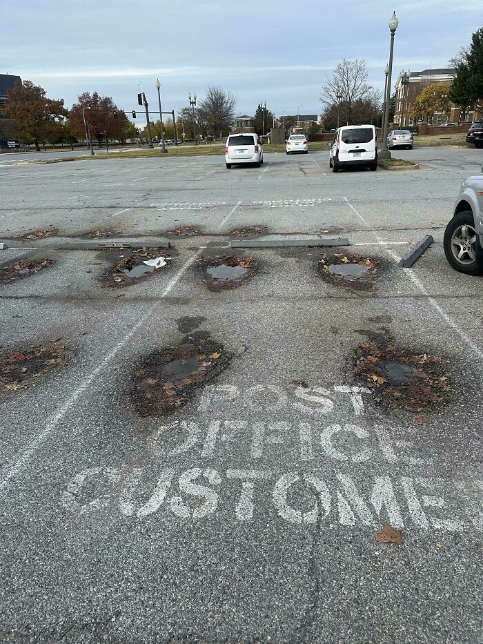 Worn-down parking area with faded "Post Office Customer" paint, illustrating the passage of time.