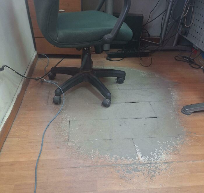 Worn-down floor showing the effects of time beneath an office chair in a workspace.