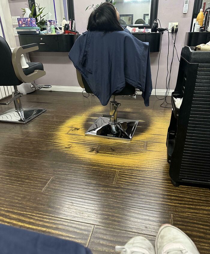 Worn-down floor showing a ring pattern around a salon chair, illustrating the passage of time.