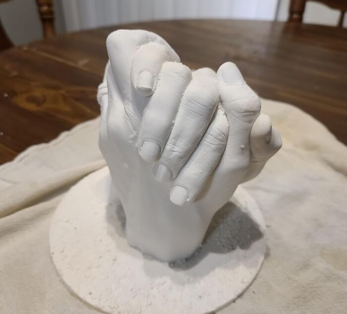 A plaster sculpture of intertwined hands on a wooden table, capturing creative treasures in art.