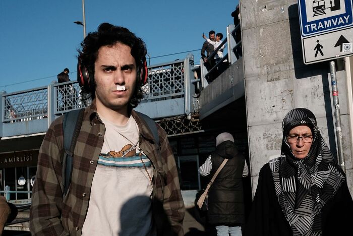 Street photographer captures hilarious accidental moment with a young man and a woman under a tramway sign.