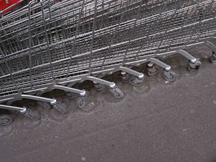 Shopping carts with worn-down wheels in a concrete groove, illustrating how time affects everyday objects.