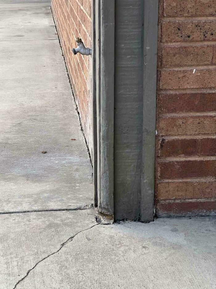 Cracked pavement and worn-down wall corner showing effects of time.