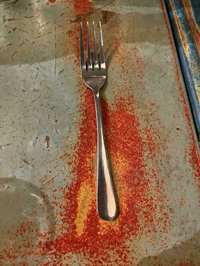 A worn-down fork on a weathered, colorful surface illustrating the passage of time.