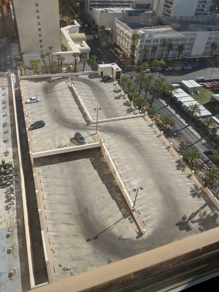 Worn-down parking lot with visible faded tire marks, showcasing the passage of time in an urban environment.