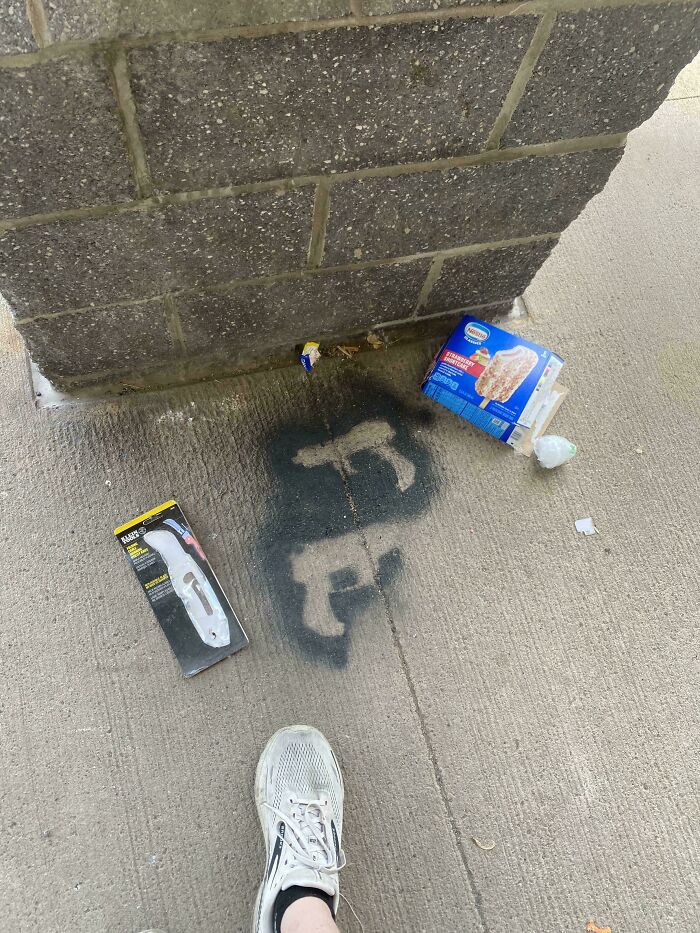 Litter and spray-painted images on ground; people being jerks by vandalizing public space.