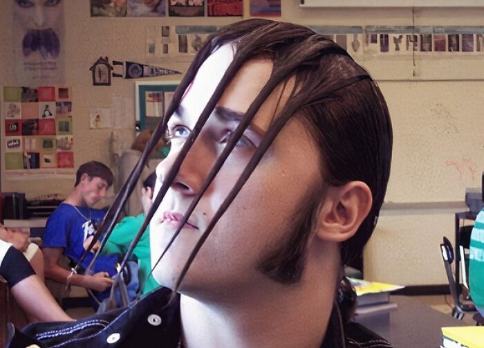 Unusual hairstyle with long strands draped over a person's face in a classroom setting, showcasing a hair accident.