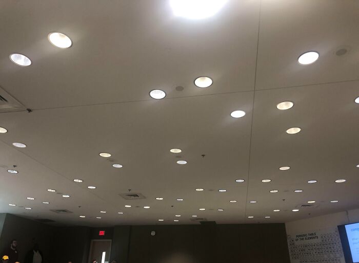 Ceiling with numerous lights, exemplifying unfortunate public interior designs, in a dimly lit room.