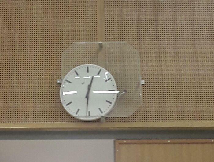 Wall clock partially obstructed by glass, showcasing unfortunate public interior design.