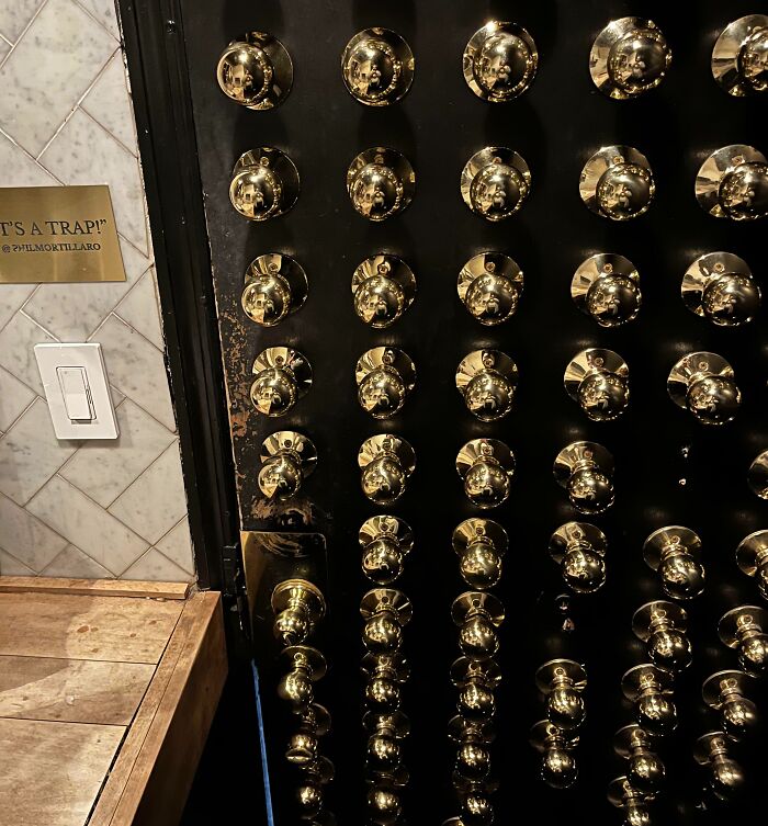 Door covered in numerous gold doorknobs, exemplifying unfortunate public interior design choices.