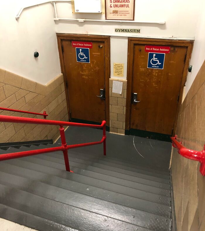 Stairs leading to gymnasium doors marked for disabled access, illustrating unfortunate public interior designs.