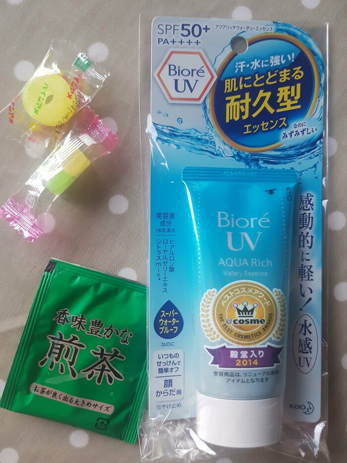 Biore UV Aqua Rich sunscreen, green tea sachet, and candy; cool products with surprises arranged on a table.