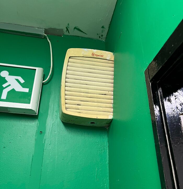 Ventilator obstructs emergency exit sign in public interior design fail.