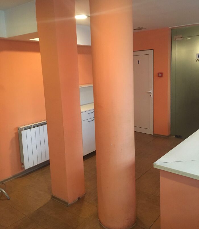 Orange room with poorly placed column blocking access to a cupboard, showcasing unfortunate interior design.