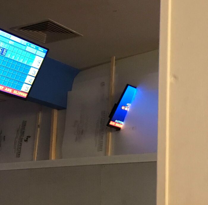 Misplaced TVs in a bowling alley displaying a score screen, showcasing unfortunate interior design choices.