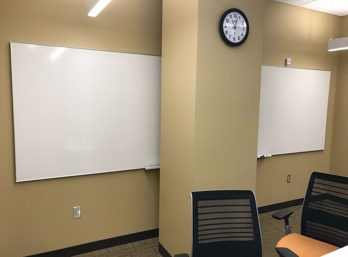 Unfortunate interior design with whiteboards on separate walls divided by a pillar, highlighting layout issues.