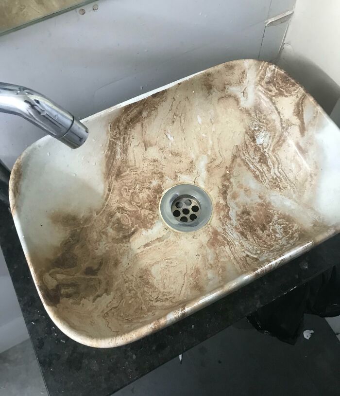 Marble sink with unfortunate public interior design choice, featuring brown swirl patterns resembling dirt stains.